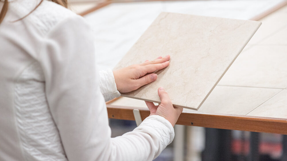 Woman choosing a new ceramic floor tile in a construction store.